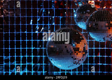 Glänzende Disco-Bälle an einem Partyvorhang unter farbigen Lichtern, Platz für Text Stockfoto