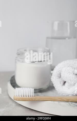 Bambuszahnbürste, Glas mit Backpulver, Handtuch und ein Glas Wasser auf einem hellen Tisch Stockfoto