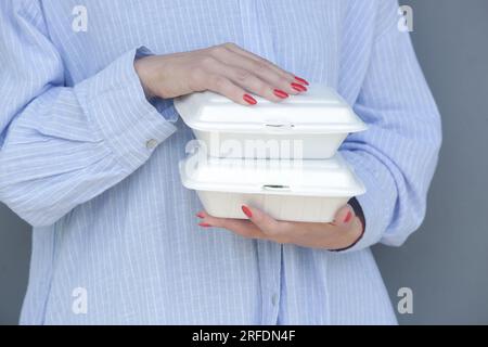 Frauenhände, die Lunchpakete aus Schaumstoff zum Mitnehmen halten. Einweg-Lebensmittelbehälter, Nahaufnahme. Stockfoto