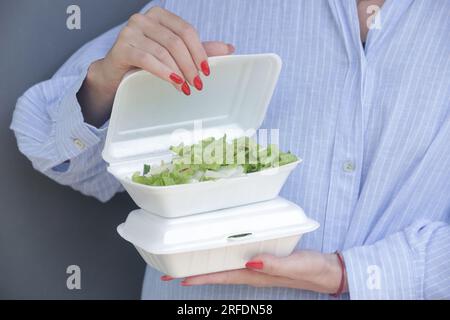 Frauenhände, die Lunchpakete aus Schaumstoff zum Mitnehmen halten. Einweg-Lebensmittelbehälter, Nahaufnahme. Stockfoto