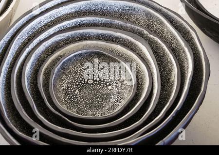 Nahaufnahme eines Sets von handgemachten organischen Tonschüsseln mit schwarz-weiß gesprenkelter Glasur. Stockfoto