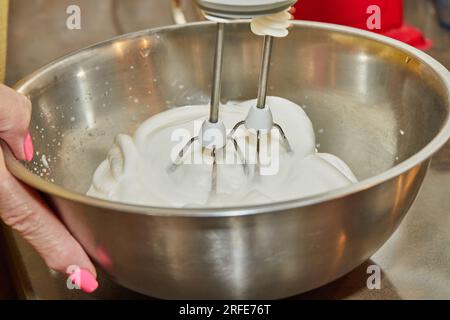 Der Koch peitscht Eiweiß mit einem Mixer in der Schüssel. Stockfoto