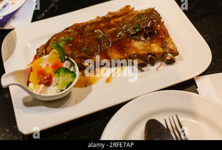 Steak mit Schweinefleisch und schwarzer Pfeffersauce garniert mit frischem Gemüsesalat Stockfoto