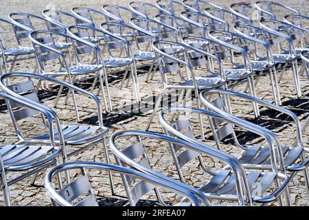 Leere Aluminiumstühle auf Kopfsteinpflaster bei Sonnenschein Stockfoto