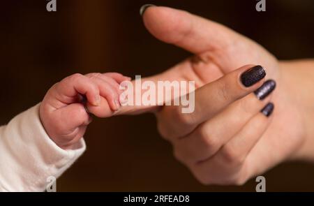 Datei Foto vom 23.01/16, ein neues Baby, das den Finger seiner Mutter hält, da fast zwei Drittel der Arbeitszeit von Frauen pro Woche unbezahlt und von offiziellen Statistiken zur Messung der Wirtschaftstätigkeit „ignoriert“ werden, so Oxfam. Stockfoto