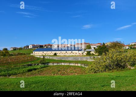 Das Dorf Pliskovica auf dem Karstplateau in Primorska, Slowenien, mit einem Solarkraftwerk auf dem Dach eines Gebäudes und einem Karstsinkloch im Balg Stockfoto