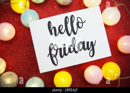 „Hello Friday“-Text auf Papierkarte Draufsicht auf rotem Bokeh-Hintergrund Stockfoto