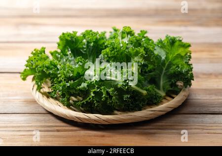 Grünkohl in einem Sieb vor einem Holzhintergrund. Grünkohl. Stockfoto