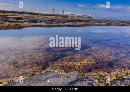 Whitby East Beach bei Ebbe mit Blick über die Schieferfelsen in Richtung East Pier und Leuchttürme. Stockfoto