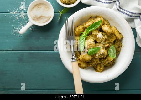 Kartoffelgnocchi. Traditionelle hausgemachte Kartoffelgnocchi mit Pesto-Sauce, Küchentisch und Basilikum auf einem alten rustikalen türkisfarbenen Küchentisch. Traditionelle Stockfoto