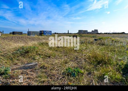 Alte Versandcontainer am Dungeness Beach an der Südküste Großbritanniens. Kilometerlange einsame, windige Gräser und Kieselstrand sowie ein einsames Kraftwerk! Stockfoto