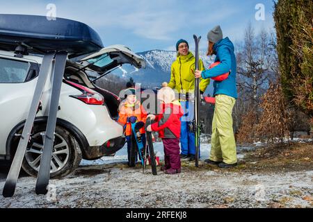 familienmutter, Vater und zwei Kinder stehen mit Ski über den Bergen Stockfoto