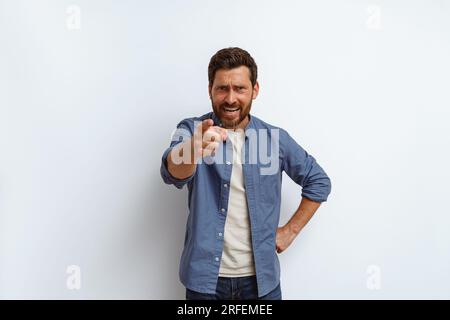 Ein gutaussehender Mann, der über weißem Hintergrund steht und verärgert und wütend auf dich vor der Kamera zeigt Stockfoto