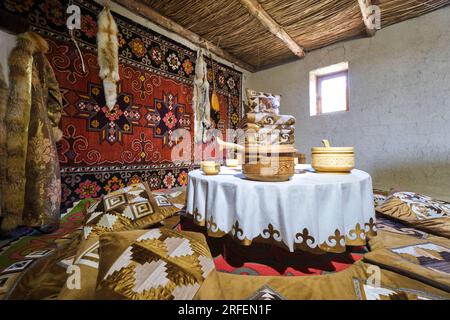 Blick auf ein traditionelles kasachisches Familienleben, Esszimmer mit niedrigem Tisch und Holzschüsseln zum Servieren. In der alten Festung, dem Zitadellen-Museum in Shymkent, Stockfoto