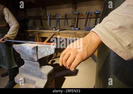 Blick auf einen traditionellen, alten, lokalen kasachischen Schmied, Details von Hand und heißem Eisenstab auf einem Amboss. In der alten Festung, dem Zitadellen-Museum in Shymke Stockfoto