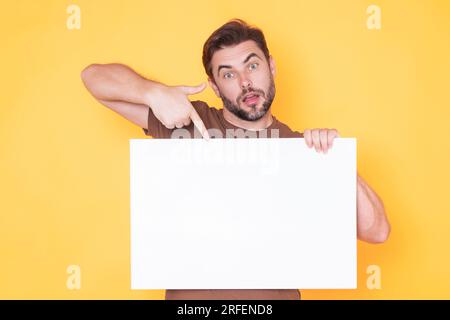 Der Mann hält ein Schild mit Kopierraum. Plakat bereit für Kopiergerät. Signieren Sie in den Text im Kopierbereich. Ein Mann mit leerem Schild im Studiohintergrund Stockfoto