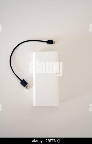 Weiße Powerbank mit isoliertem schwarzem Kabel. Weißer Hintergrund. Stockfoto