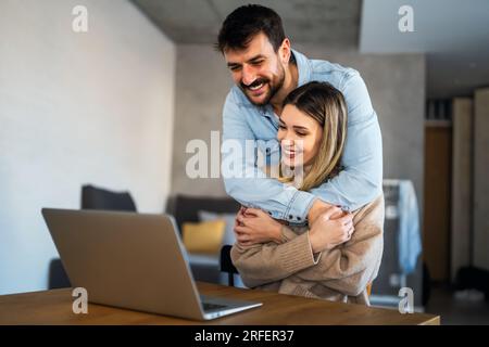 Junge glückliche Paare, die online Videoanrufe führen, sich mit Verwandten unterhalten, mit Freunden kommunizieren Stockfoto