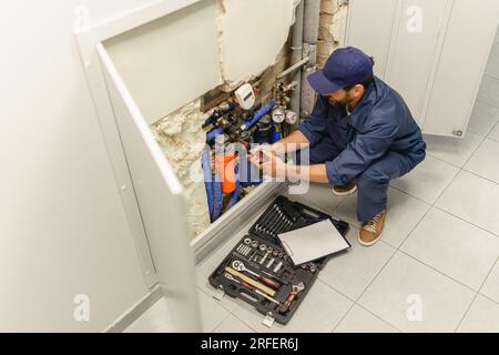 Handwerker in Uniform repariert Wasserversorgungssystem zu Hause verwendet einen verstellbaren Schraubenschlüssel Stockfoto