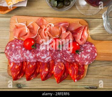 Spanische Tapas: Auf Holzbrettscheibchen werden Würstchen und Jamon serviert Stockfoto