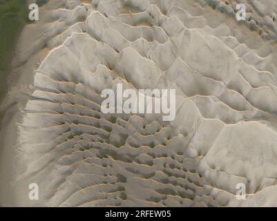 Frankreich, Somme, Baie de Somme, Le Hourdel, soleil couchant sur le Hourdel à l'extrémité du cordon de galets alors que la Marée basse dévoile les méandres des chenaux et les reliefs des Bancs de Sable (vue aérienne) Stockfoto