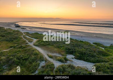 Frankreich, Somme, Baie de Somme, Le Hourdel, soleil couchant sur le Hourdel à l'extrémité du cordon de galets alors que la Marée basse dévoile les méandres des chenaux et les reliefs des Bancs de Sable (vue aérienne) Stockfoto