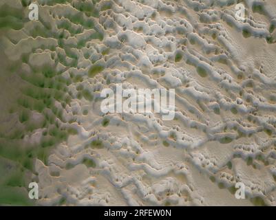 Frankreich, Somme, Baie de Somme, Le Hourdel, soleil couchant sur le Hourdel à l'extrémité du cordon de galets alors que la Marée basse dévoile les méandres des chenaux et les reliefs des Bancs de Sable (vue aérienne) Stockfoto