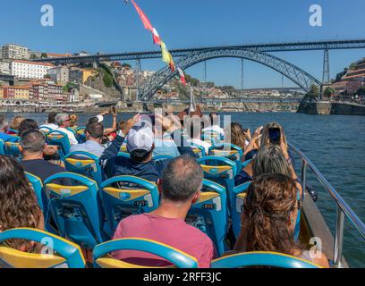 Porto, Portugal. Besucher, die eine Besichtigungstour auf einem Tourboot auf dem Douro River genießen. Sie nähern sich der Brücke Dom Luis I. Stockfoto