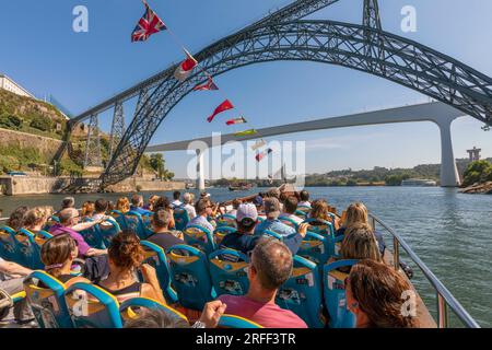 Porto, Portugal. Besucher, die eine Besichtigungstour auf einem Tourboot auf dem Douro River genießen. Sie nähern sich der Brücke Dom Luis I. Stockfoto