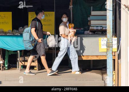 SAMUT PRAKAN, THAILAND, FEBRUAR 02 2023, Frauen gehen die Straße entlang mit einem Kind in den Händen Stockfoto