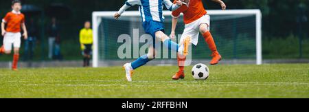 Europäisches Fußballspiel zwischen Jugendmannschaften. Junge Schuljungen, die Fußball spielen. Junior-Wettkampf zwischen Spielern, die laufen und treten. Stockfoto