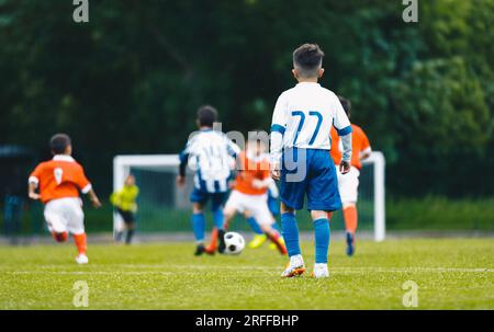 Junge Schuljungen, die ein Fußballspiel spielen. Europäisches Fußballspiel zwischen Jugendmannschaften. Junior-Wettkampf zwischen Spielern, die einen Fußball-Ba laufen und treten Stockfoto