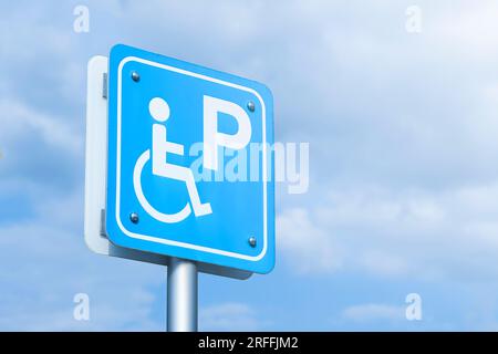 Ein blaues Parkschild für Behinderte vor blauem Himmel. Stockfoto