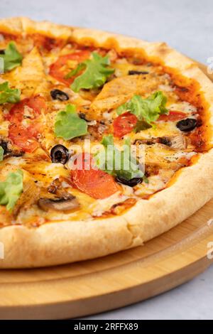 Fleischlose Pizza mit Pilzen Nahaufnahme auf einer Holzplatte, auf hellem Hintergrund Stockfoto