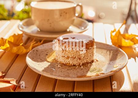 Fallen gesunder süßer Karottenkuchen unter Agavesirup. Kein Backen und kein Zuckerdessert mit einer Tasse Kaffee unter harten Schatten. Stockfoto