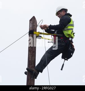 Techniker, der ein Breitband-Glasfaserkabel an einen Pol anschließt Stockfoto