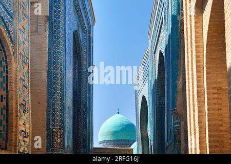 Schöner historischer Friedhof von Shahi Zinda Eingangstor mit fein dekorierten blauen und türkisfarbenen Steinmosaiken Mausoleen in Samarkand, Usbekistan. Stockfoto
