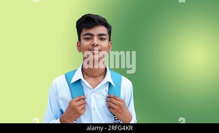 Porträt eines glücklichen indischen Teenagers auf dem College oder Schuljungen mit Rucksack, isoliert auf gelbem grünen Hintergrund. Lächelnder junger asiatischer Junge, der auf Ca Stockfoto