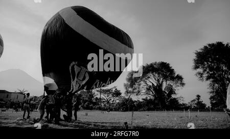 Teilnehmer des Wonosobo Air Balloon Festival 2022 versuchen, einen Ballon zu fliegen, indem sie die Luft im Ballon erwärmen. Stockfoto