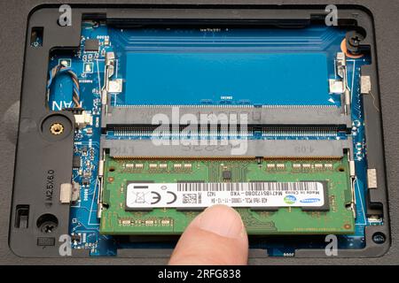 Sichern eines typischen RAM-Speichermoduls nach dem Einsetzen in einen Speichersockel in einem Laptop. Der Finger drückt nach unten, um das Modul in den Clips einrasten zu lassen. (3 von 4) Stockfoto