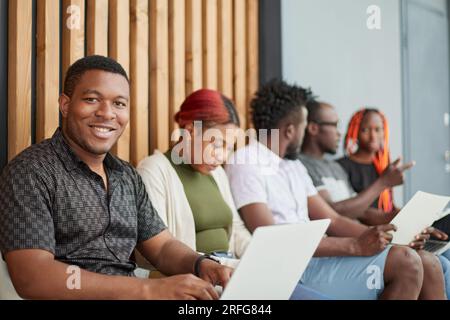 Eine Gruppe schwarzer Kandidaten wartet auf ein Interview im Büro. Stockfoto