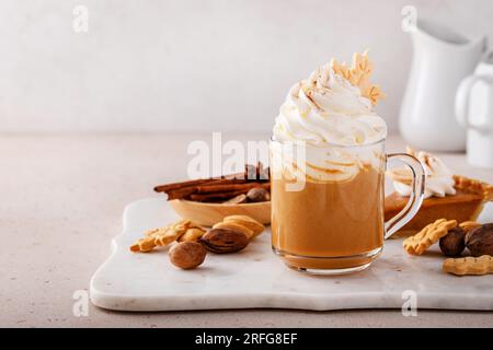Kürbis-Gewürz-Latte in einem Becher garniert mit Schlagsahne und Zimt Stockfoto