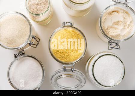 Lebensmittelaufbewahrung, kulinarisches und Essenskonzept – Nahaufnahme von Gläsern mit verschiedenen Arten von Mehl, Salz und Zucker auf weißem Hintergrund, Draufsicht Stockfoto