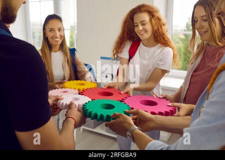 Eine Gruppe von Personen verbindet einfarbige Zahnräder, um eine Ausrüstung herzustellen. Stockfoto