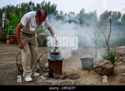 (230803) -- TONGLIAO, 3. August 2023 (Xinhua) -- Bai Shun kocht Wasser in seinem Haus in Bulteger Gacha, Horqin Left Wing Rear Banner von Tongliao City, Nordchina innere Mongolei Autonome Region, 2. August 2023. Im Zentrum des Horqin Sandy Land befindet sich Bulteger Gacha, ein kleines Dorf im Horqin Left Wing Rear Banner von Tongliao City, das früher unter Wüstenbildung litt. Seit 2002 hat Bai Shun, ein lokaler mongolischer Bauer, seine Familie in diesem Dorf Wurzeln geschlagen und sich der Kontrolle der Wüstenbildung verschrieben. Die Überlebensrate der gepflanzten Bäume war zu Beginn aufgrund des Mangels an o niedrig Stockfoto