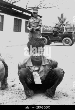 SAIGON, VIETNAM - Februar 1968 - Ein jugendlicher Vietcong-Kämpfer, schwer bewacht, wartet auf ein Verhör nach der Gefangennahme bei den Angriffen auf die Hauptstadt C. Stockfoto