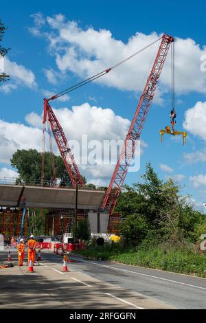 Harefield, Großbritannien. 3. August 2023. Der Bau des HS2 High Speed Rail Colne Valley Viaduct durch Align JV wird fortgesetzt. Die Moorhall Road (abgebildet) in Harefield, im Londoner Stadtteil Hillingdon, ist derzeit für den Verkehr gesperrt, da auf der anderen Straßenseite temporäre Stützstrukturen unter Viaduksegmenten errichtet werden, die von einem Kran zusammengebaut werden. Das Colne Valley Viaduct überquert die Moorhall Road zwischen Korda Lake und Savay Lake, südlich des Grand Union Canal. Die Infrastruktur- und Projektbehörde hat das HS2-Milliarden-Pfund-Projekt zwischen London an verlegt Stockfoto