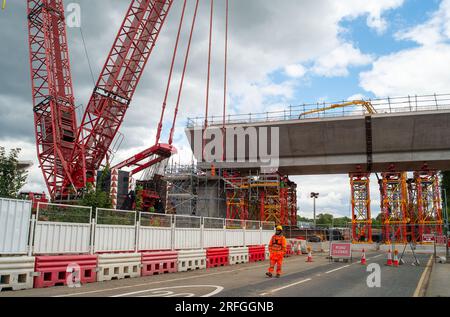 Harefield, Großbritannien. 3. August 2023. Der Bau des HS2 High Speed Rail Colne Valley Viaduct durch Align JV wird fortgesetzt. Die Moorhall Road (abgebildet) in Harefield, im Londoner Stadtteil Hillingdon, ist derzeit für den Verkehr gesperrt, da auf der anderen Straßenseite temporäre Stützstrukturen unter Viaduksegmenten errichtet werden, die von einem Kran zusammengebaut werden. Das Colne Valley Viaduct überquert die Moorhall Road zwischen Korda Lake und Savay Lake, südlich des Grand Union Canal. Die Infrastruktur- und Projektbehörde hat das HS2-Milliarden-Pfund-Projekt zwischen London an verlegt Stockfoto