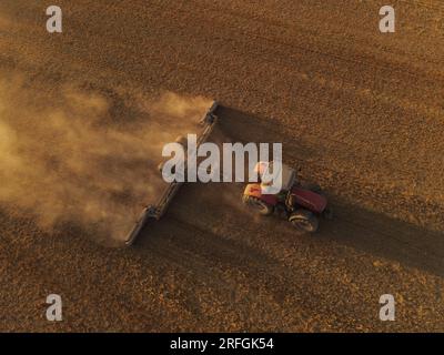 Ein Massey Ferguson-Traktor, von oben gesehen, kultiviert ein Feld nach einem extrem trockenen Sommer, um es für den Anbau vorzubereiten. Stockfoto