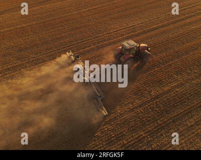 Ein Massey Ferguson-Traktor, von oben gesehen, kultiviert ein Feld nach einem extrem trockenen Sommer, um es für den Anbau vorzubereiten. Stockfoto